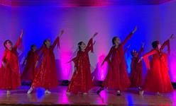 Eine Gruppe von Frauen in roten Kleidern tanzt auf einer Bühne